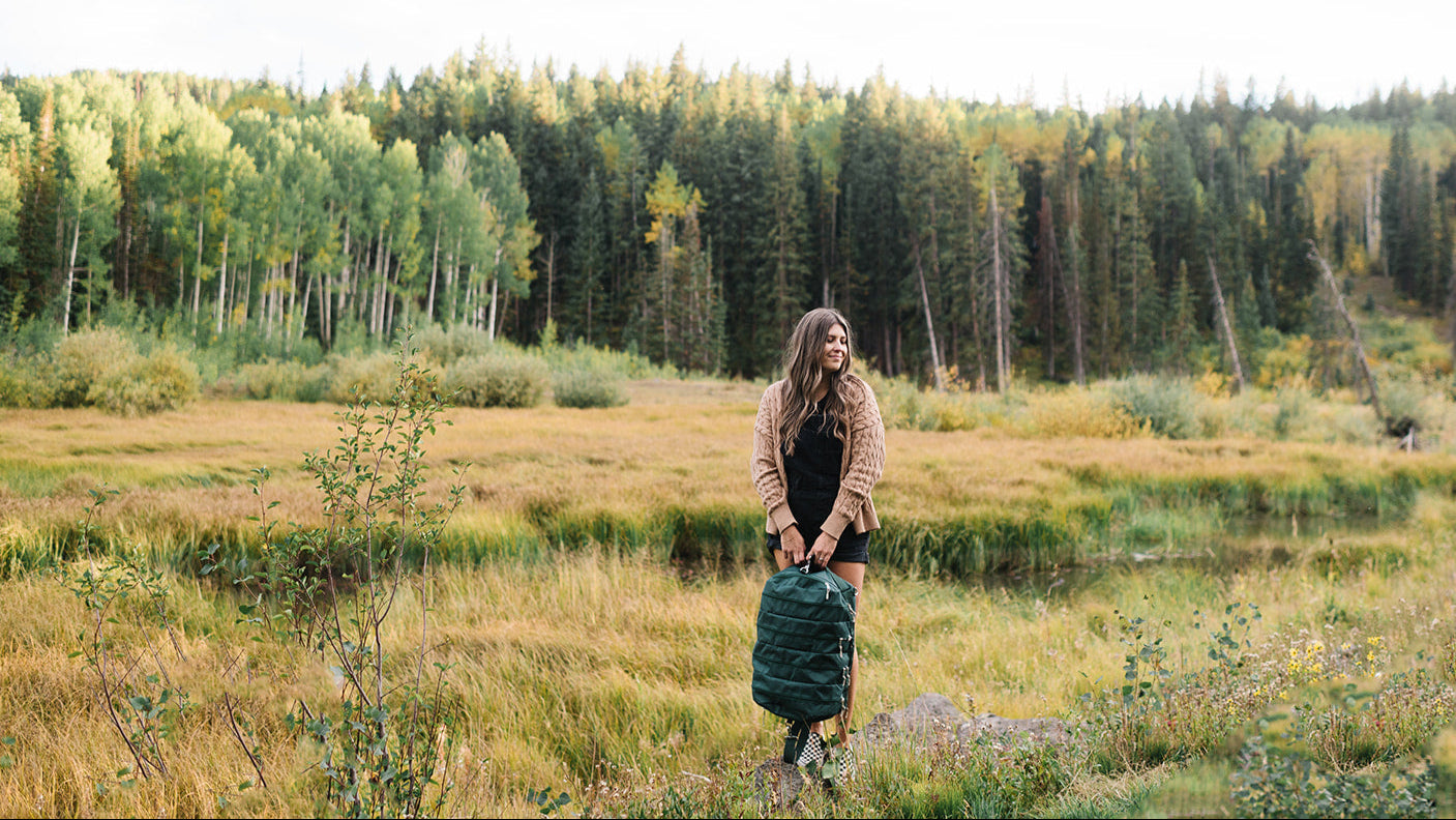 Woman standing in a field with trees and a clear sky